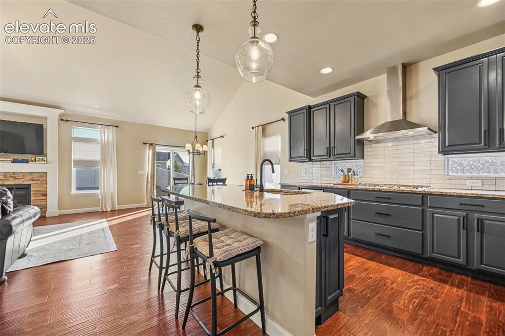 Image 11 of 47: Open-concept kitchen with dark cabinetry, granite countertops, tile backspl