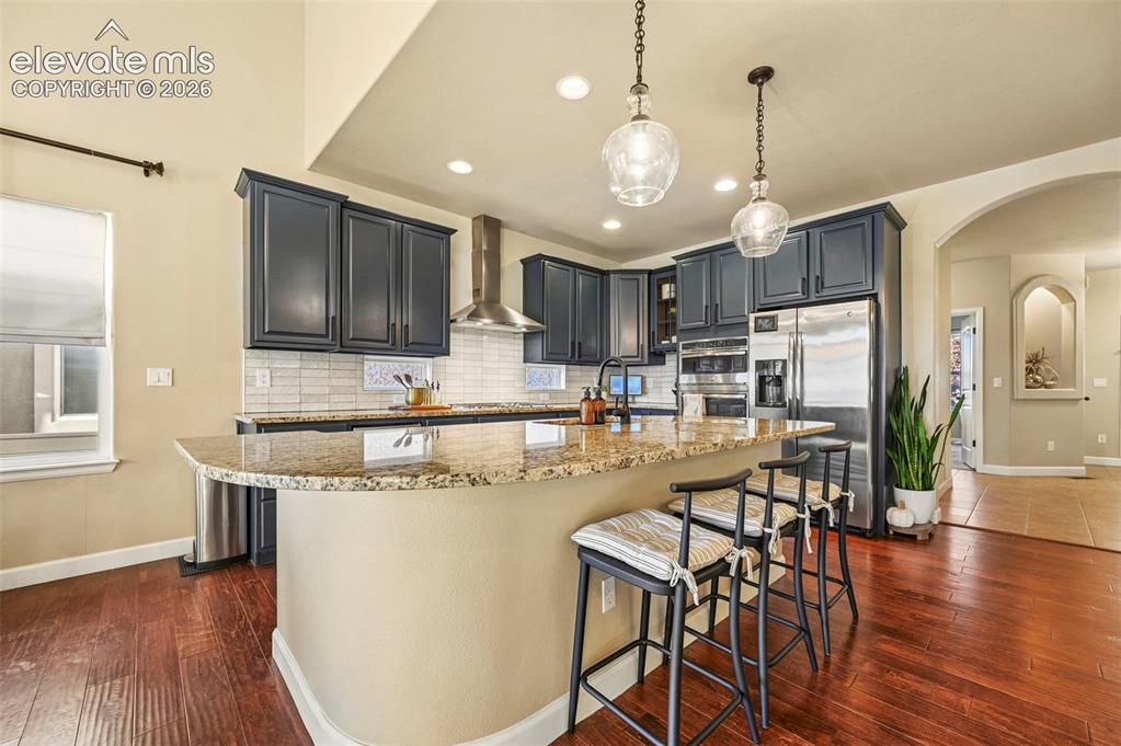 Image 12 of 47: Kitchen featuring dark cabinetry, stainless steel appliances, a tile backsp