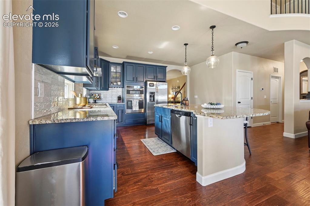 Image 12 of 46: Kitchen featuring navy blue cabinetry, stone countertops, stainless steel a