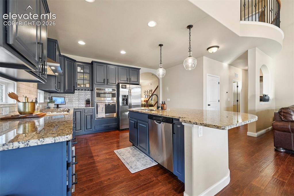 Image 13 of 47: Kitchen featuring wood-finish flooring, custom cabinetry, granite counterto