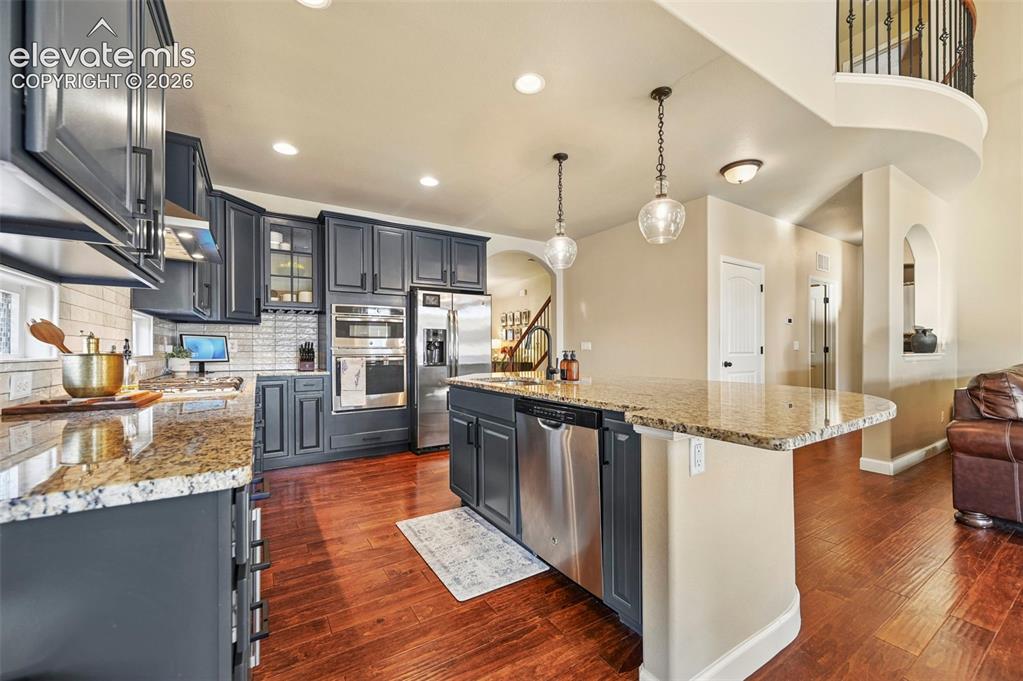 Image 13 of 47: Kitchen featuring dark cabinetry, stainless steel appliances, granite count
