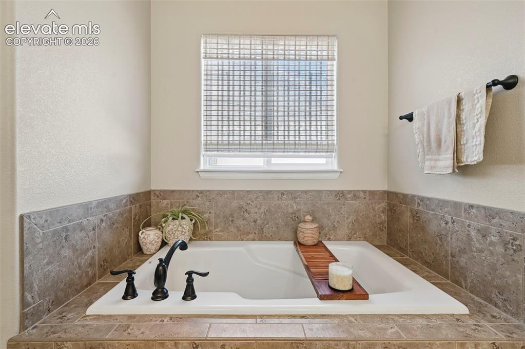 Image 20 of 47: Built-in soaking tub with a tiled surround, black hardware, and an adjacent
