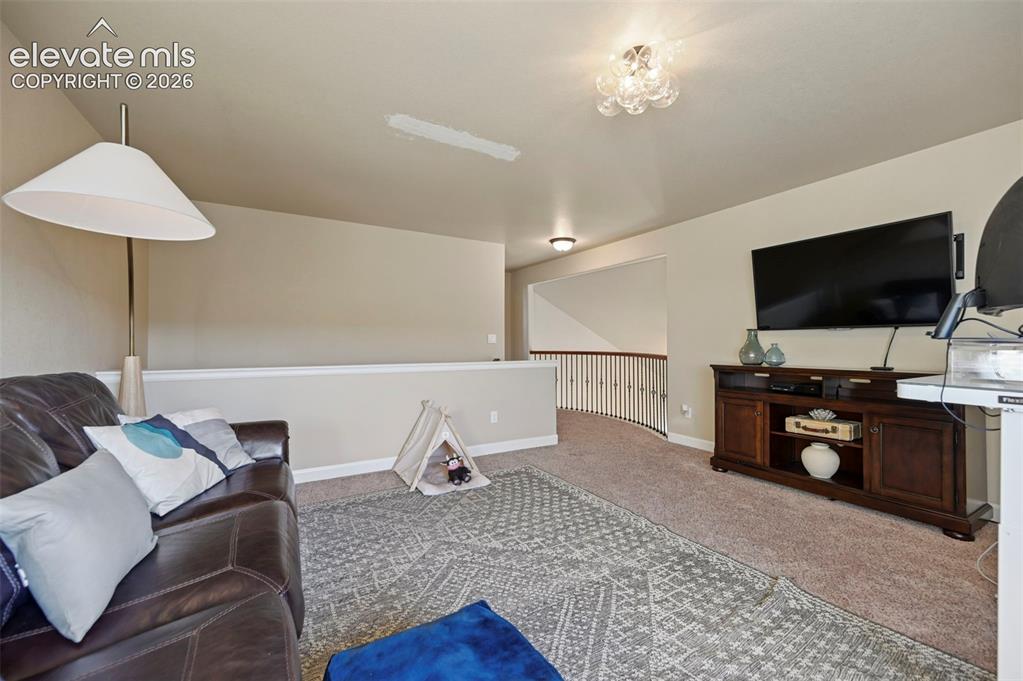 Image 25 of 47: Carpeted open area featuring a wood media console, painted walls, and a dec