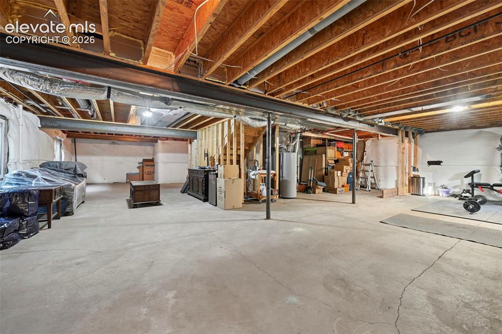 Image 32 of 47: Unfinished basement featuring exposed wood joists, concrete flooring, and s