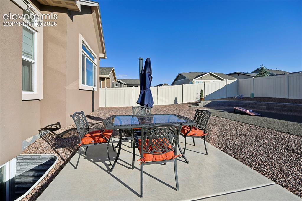 Image 33 of 47: Concrete patio with a stucco exterior, surrounded by gravel landscaping and