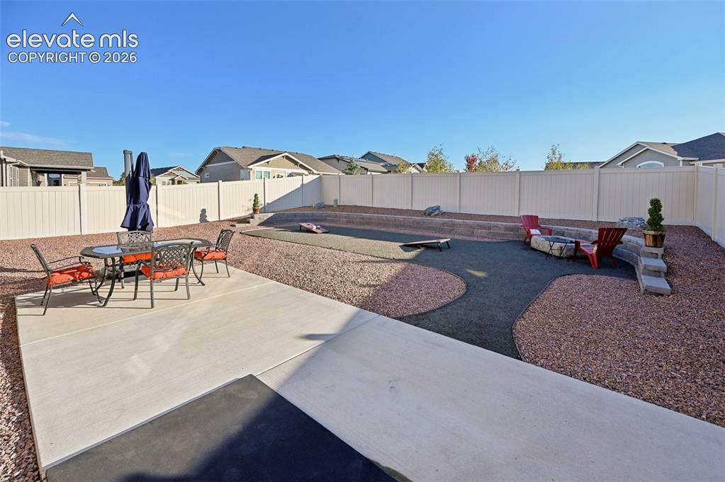 Image 34 of 46: Concrete patio and expansive gravel landscaping featuring a built-in fire p