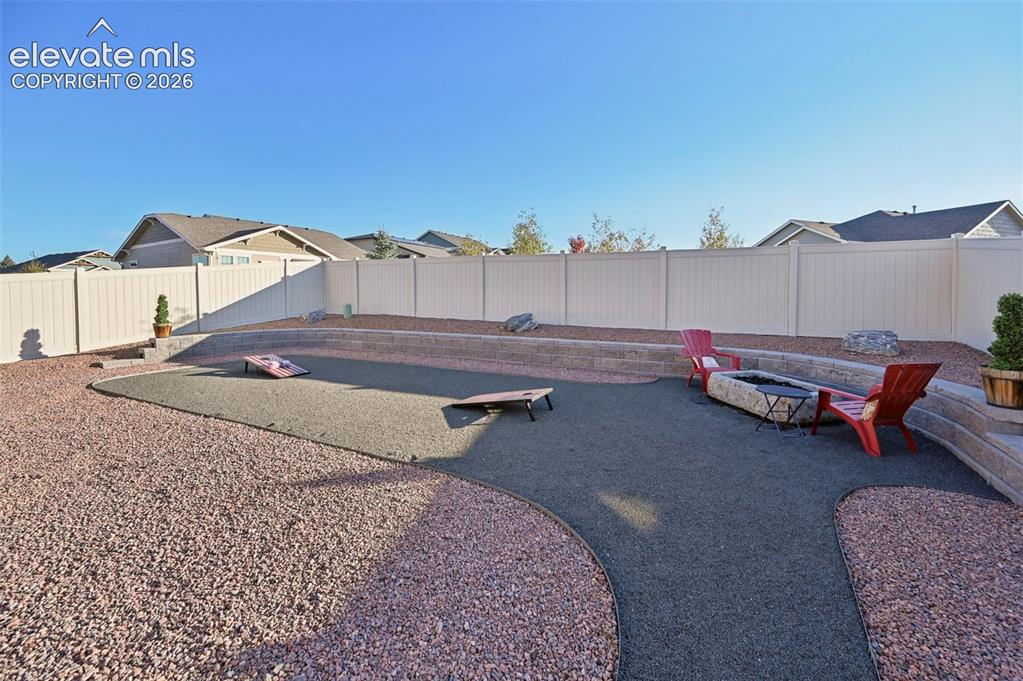 Image 35 of 47: Multi-level backyard featuring a fire pit, privacy fencing, and stone hards