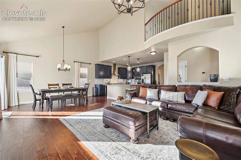 Image 7 of 47: Open-concept living area with vaulted ceiling, wood-finish flooring, and a