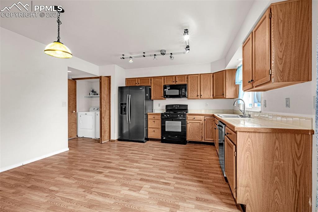 Image 11 of 41: Kitchen featuring wood-finish flooring, oak cabinetry, black appliances, an