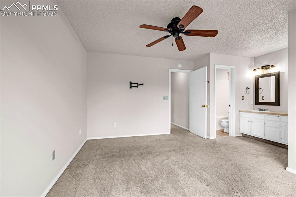 Image 13 of 41: Carpeted room with a ceiling fan, light gray painted walls, and a wall-moun
