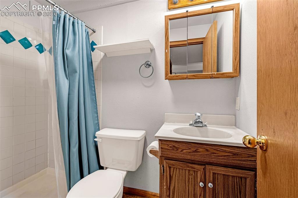 Image 24 of 41: Bathroom featuring a wood-finish vanity with a built-in sink, a wall-mounte
