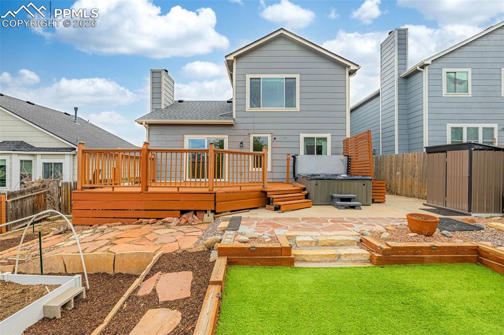 Image 27 of 41: Multi-level backyard featuring a spacious wood deck, flagstone patio, and a