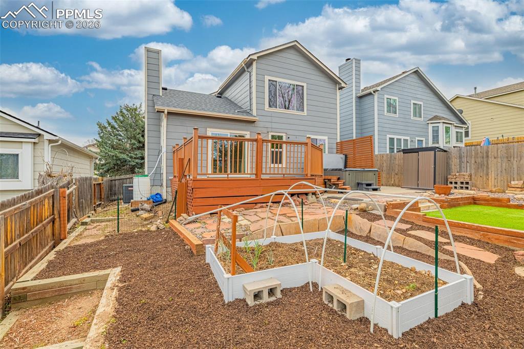 Image 28 of 41: Expansive backyard featuring a multi-level wood deck, raised garden beds, a