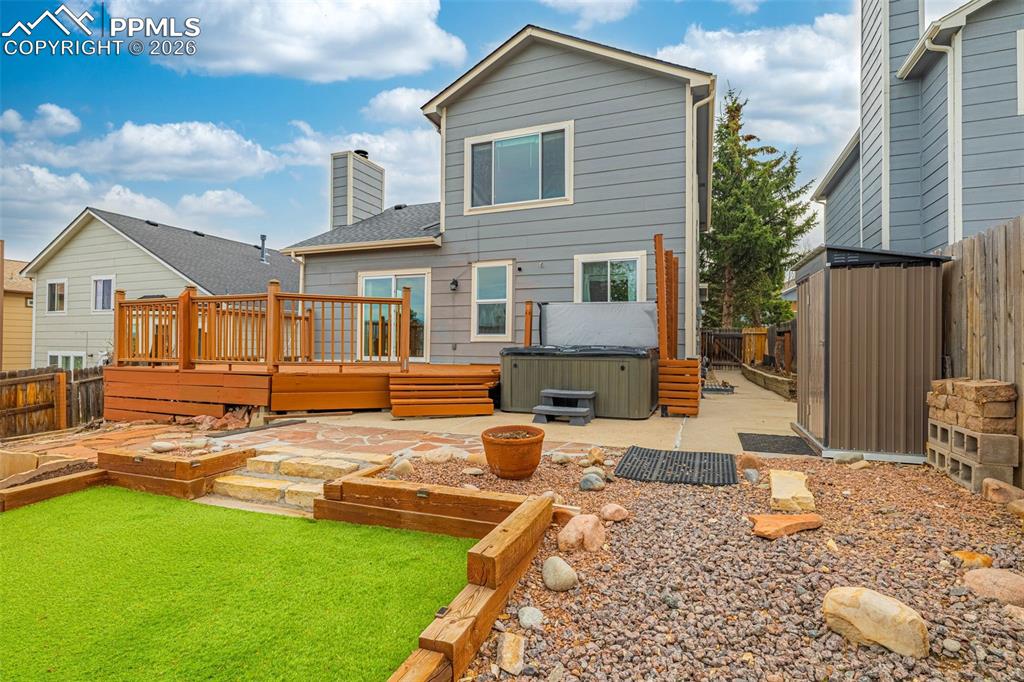 Image 29 of 41: Tiered backyard featuring a wooden deck with railing, a built-in hot tub, a