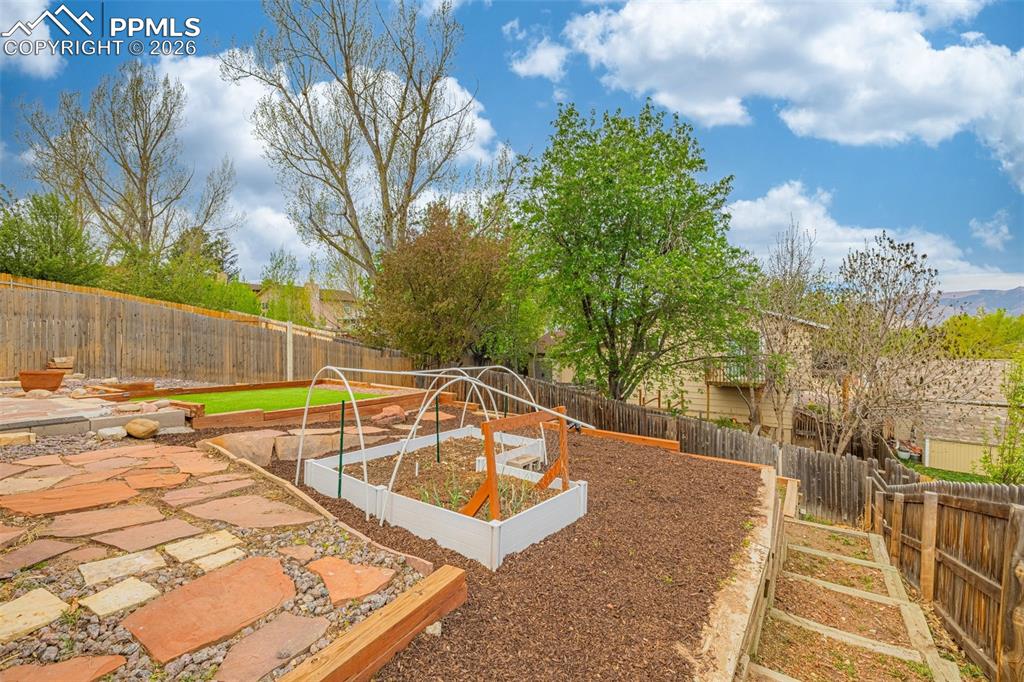 Image 30 of 41: Terraced backyard featuring flagstone pathways and multiple raised garden b
