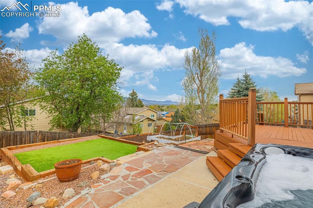 Image 31 of 41: Multi-level backyard featuring a wood deck, flagstone patio, hot tub, and a