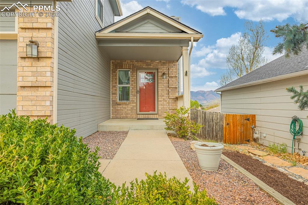 Image 4 of 41: Covered entryway with a red-paneled door, brick façade accents, and horizon
