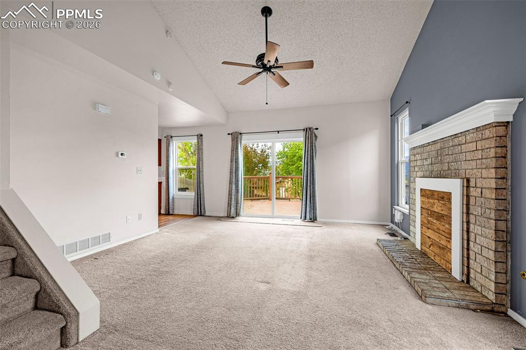 Image 6 of 41: Spacious living area featuring vaulted ceilings, a ceiling fan, and a brick