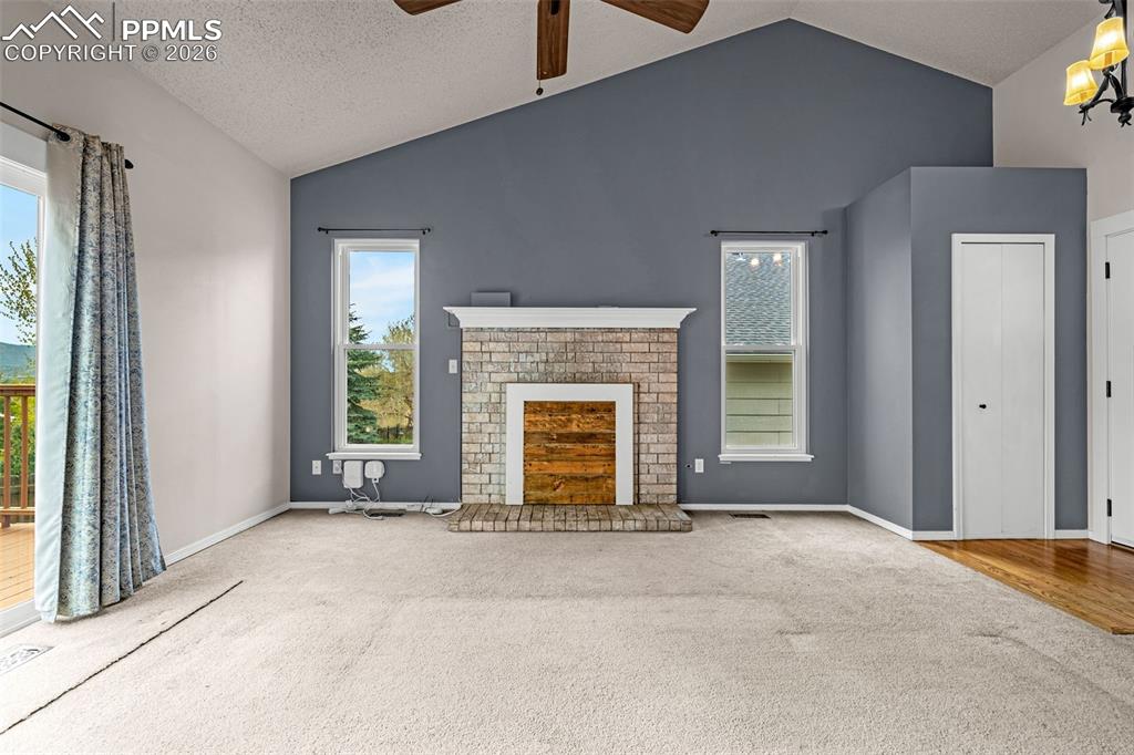 Image 7 of 41: Vaulted ceiling living area featuring a brick fireplace with wood-finish in