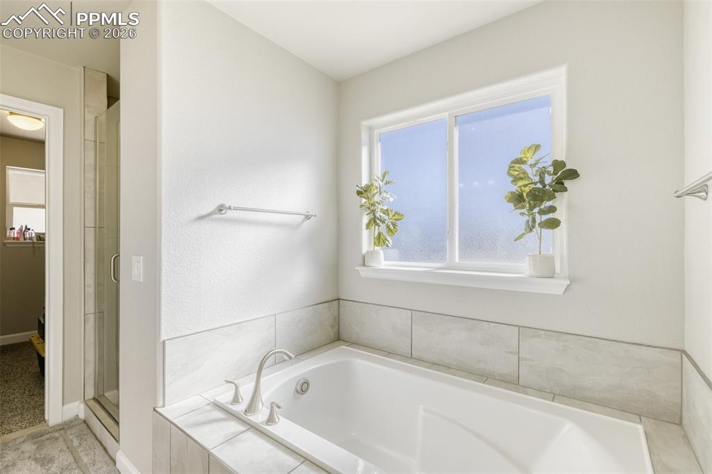 Image 21 of 42: primary bathroom tub and stand-alone shower with walk-in closet