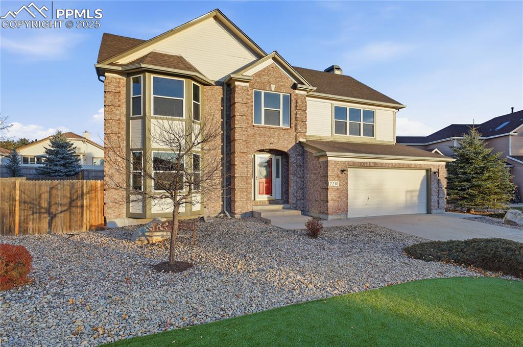 Caption: Traditional-style home with concrete driveway, a chimney, a garage, and brick siding