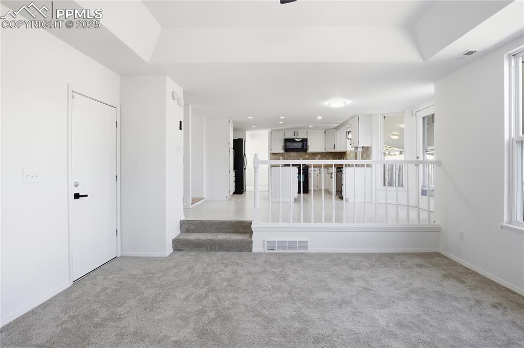 Image 16 of 42: Unfurnished living room with light carpet and stairway
