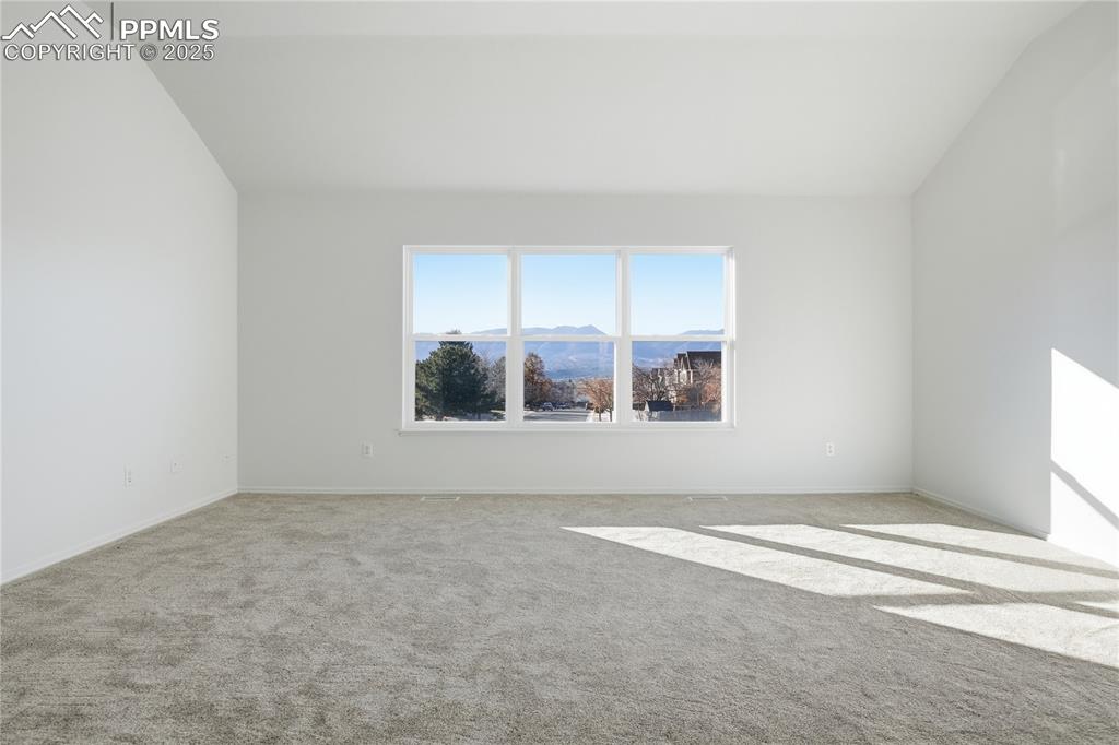 Image 18 of 42: Carpeted spare room featuring a mountain view and vaulted ceiling