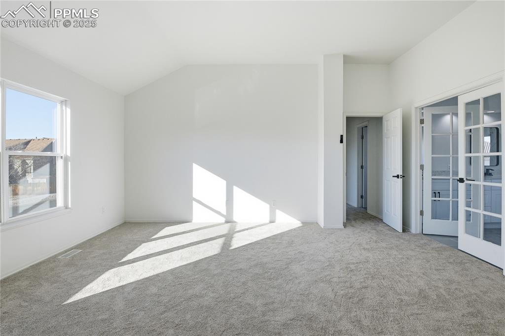 Image 19 of 42: Spare room with lofted ceiling, carpet floors, and french doors