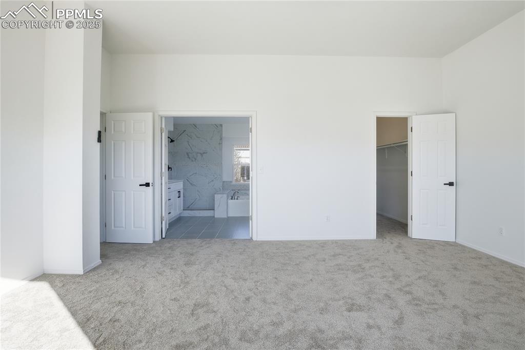 Image 20 of 42: Unfurnished bedroom with light carpet, a walk in closet, and connected bath