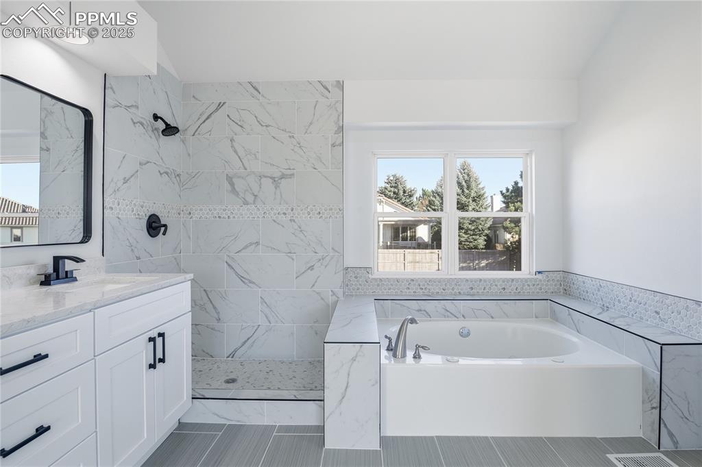 Image 21 of 42: Bathroom featuring vanity, a bath, and a marble finish shower