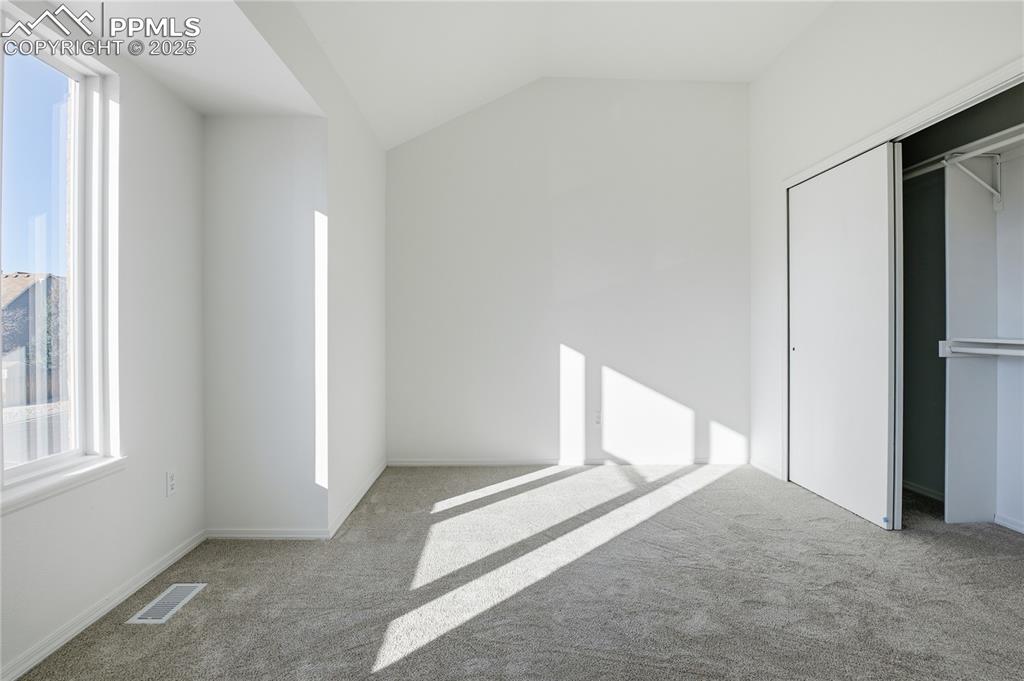 Image 26 of 42: Unfurnished bedroom with carpet flooring, vaulted ceiling, and a closet