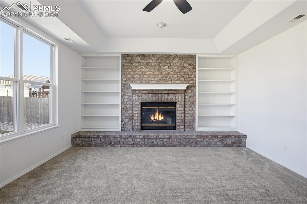 Image 5 of 42: Unfurnished living room with ceiling fan, carpet flooring, a fireplace, and