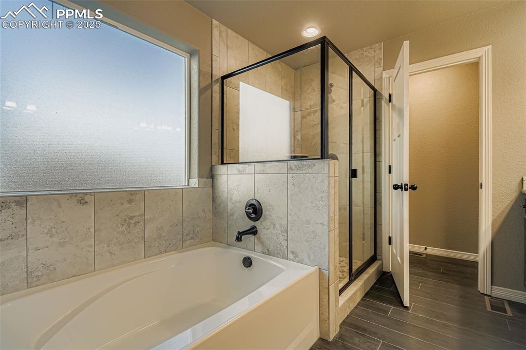 Image 16 of 28: Full bathroom featuring a bath, a stall shower, and wood finish floors