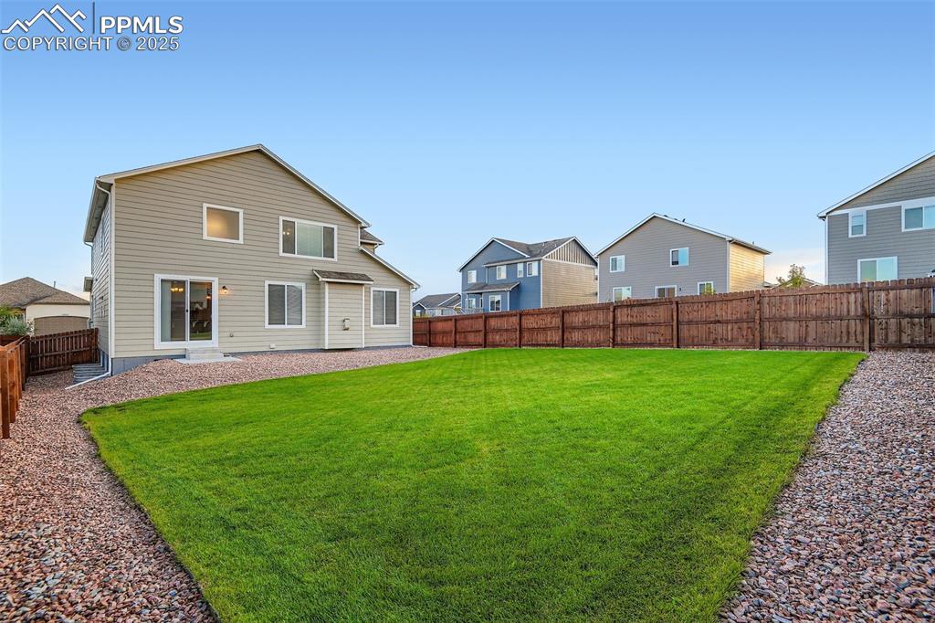 Image 28 of 28: Rear view of house with a fenced backyard