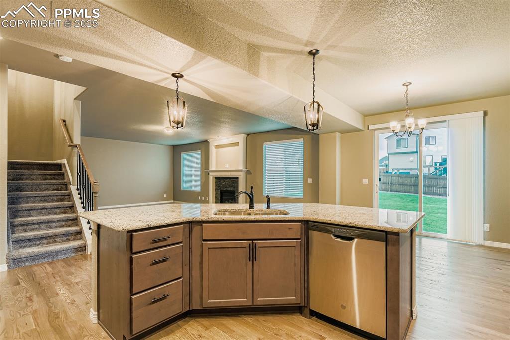 Image 9 of 28: Kitchen with a textured ceiling, an island with sink, dishwasher, a firepla