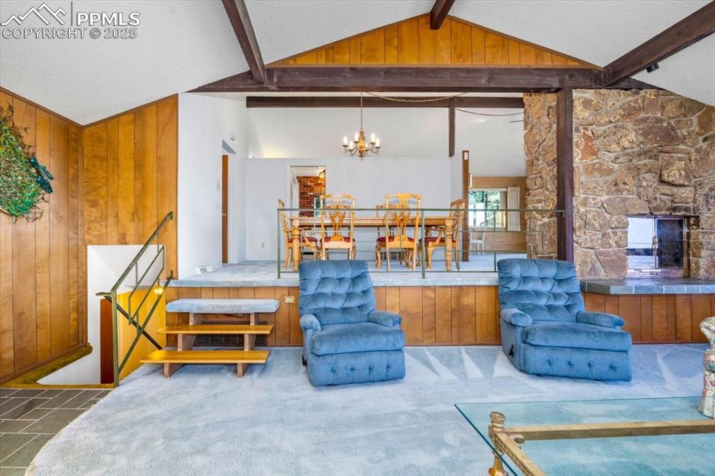 Image 10 of 38: Living room featuring wooden walls, a textured ceiling, a fireplace, and a