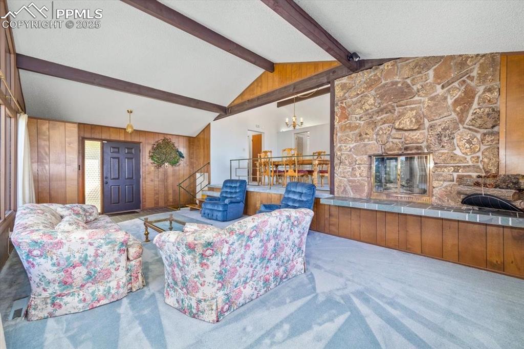 Image 11 of 38: Carpeted living area with a fireplace, wooden walls, a textured ceiling, an