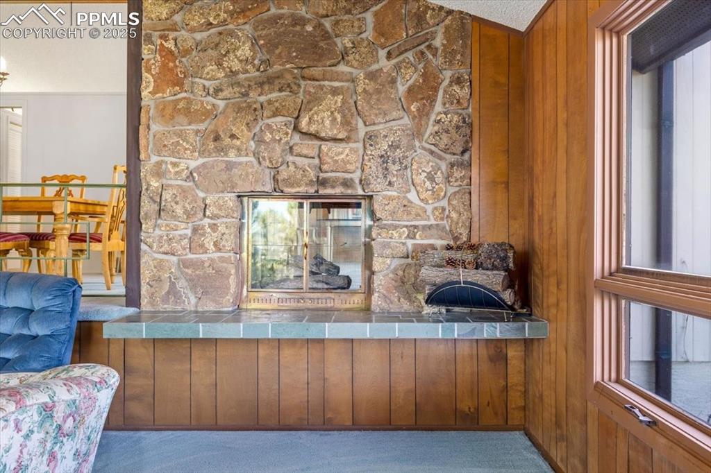 Image 12 of 38: Detailed view of a stone fireplace, carpet, and wood walls