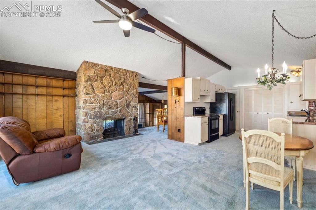 Image 15 of 38: Living room featuring light carpet, a textured ceiling, a stone fireplace,