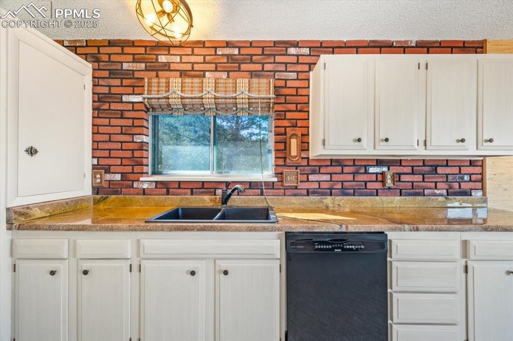 Image 17 of 38: Kitchen with black dishwasher, a textured ceiling, white cabinets, and ligh