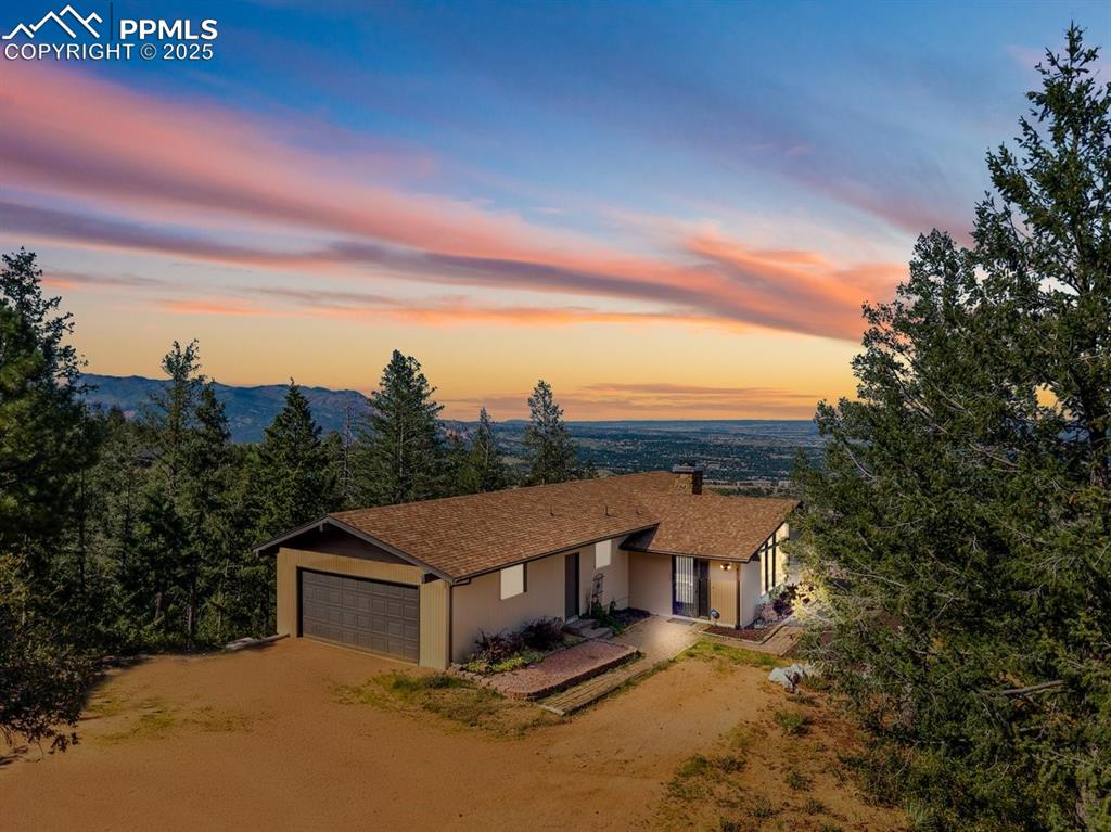 Image 2 of 38: View of front of home featuring dirt driveway, an attached garage, covered