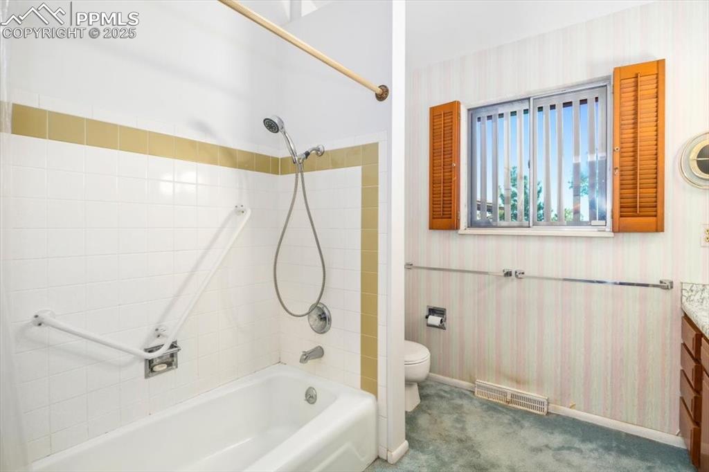 Image 22 of 38: Bathroom featuring wallpapered walls, shower / tub combination, and vanity