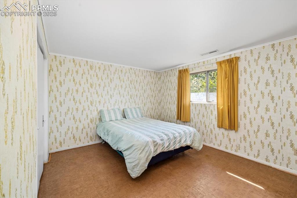 Image 27 of 38: Bedroom featuring wallpapered walls and ornamental molding