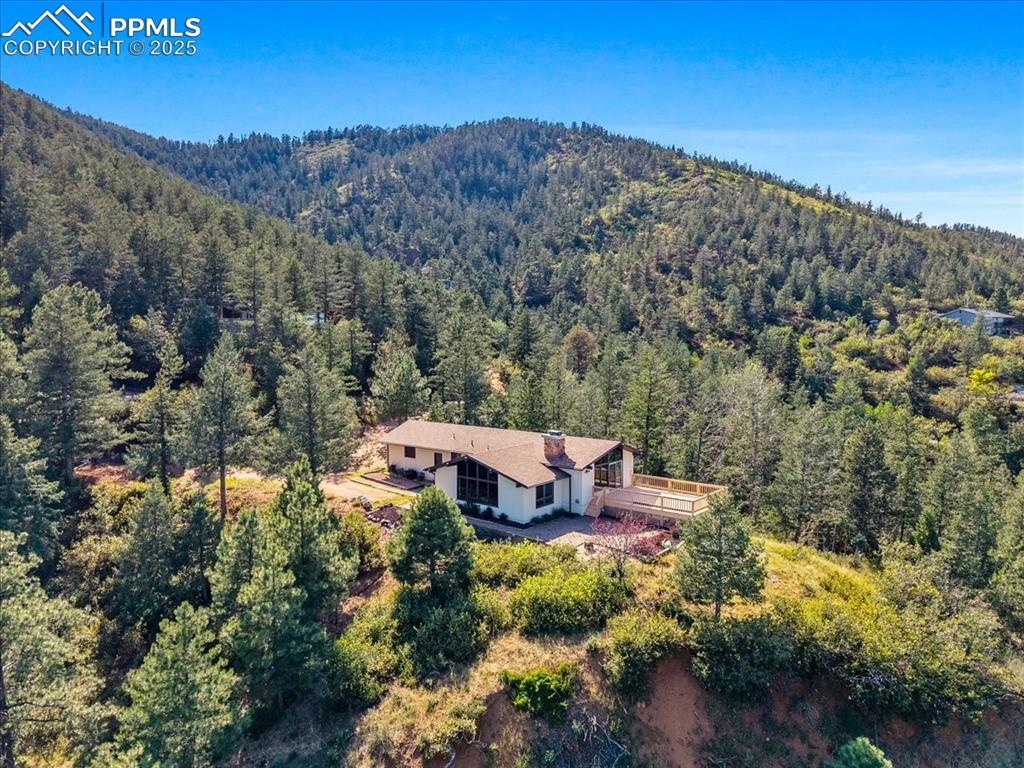 Image 3 of 38: View of subject property with a heavily wooded area and a mountain backdrop