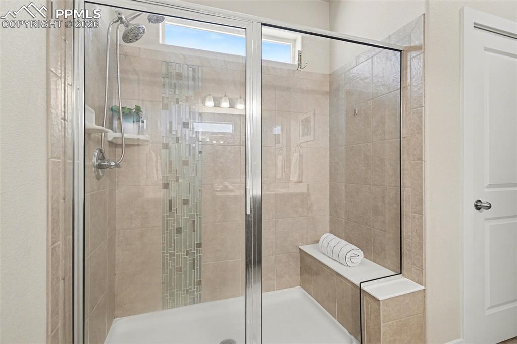 Image 11 of 37: A huge glass-enclosed standing shower with a built-in bench.