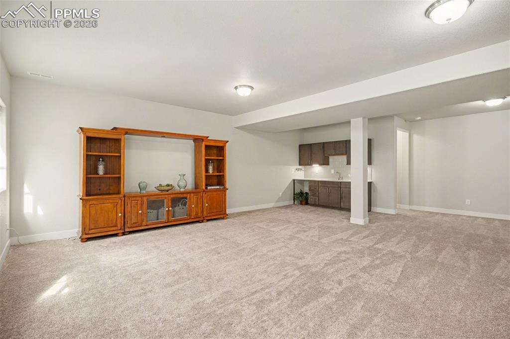 Image 27 of 37: The basement features a huge family room with soft carpeting, offering a co