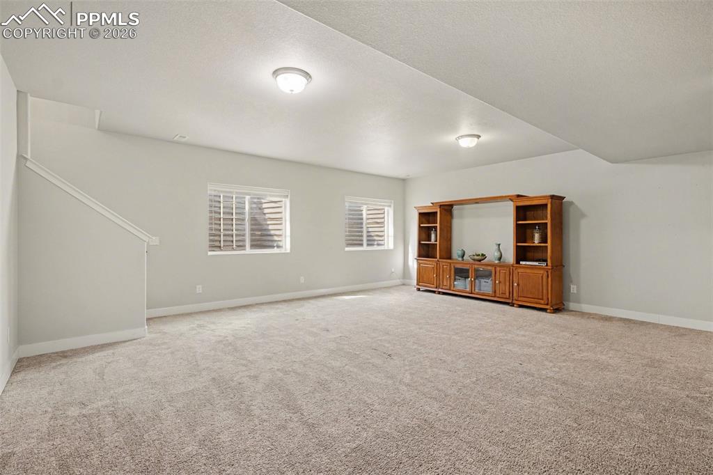 Image 28 of 37: The basement boasts a huge family room with soft carpeting and a wet bar, c