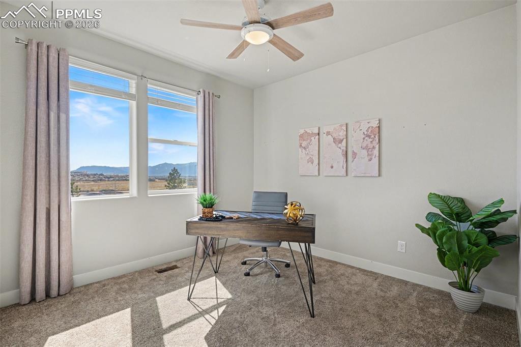 Image 6 of 37: The main-floor bedroom features soft carpeting, a ceiling fan for added com
