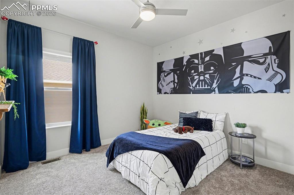 Image 7 of 37: The second main-level bedroom features soft carpeting and an open, airy fee