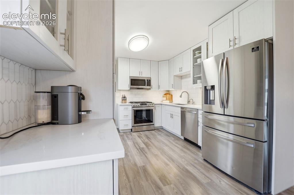 Image 11 of 38: Bright kitchen featuring white cabinetry, stainless steel appliances, a pic
